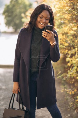 Photo for African american woman with phone in park - Royalty Free Image