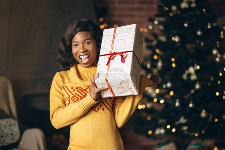 Photo for African american woman unpacking christmas gifts by chrirstmas tree - Royalty Free Image
