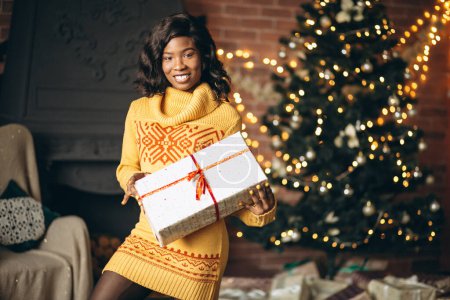 Foto de Mujer afroamericana desempacando regalos de Navidad por árbol de Navidad - Imagen libre de derechos