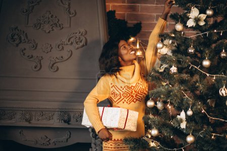 Téléchargez les photos : Femme afro-américaine décorer arbre de Noël - en image libre de droit