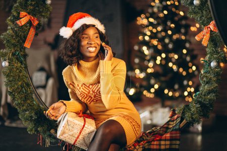Téléchargez les photos : Femme afro-américaine parlant au téléphone à Noël - en image libre de droit