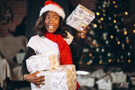 Photo for African american woman with presents by the Christmas tree - Royalty Free Image