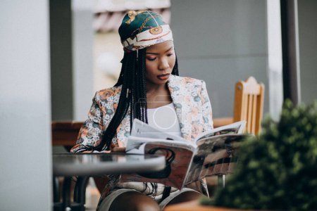 Foto de Mujer afroamericana leyendo revista en un café - Imagen libre de derechos