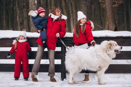 Foto de Madre con niños y perro jugando al aire libre en invierno - Imagen libre de derechos