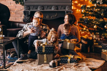 Téléchargez les photos : Grande famille la veille de Noël avec des cadeaux par arbre de Noël - en image libre de droit