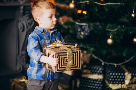 Téléchargez les photos : Petit garçon mignon avec cadeau de Noël par arbre de Noël - en image libre de droit