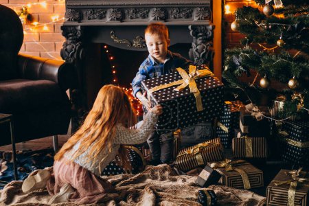Foto de Hermano con hermana con regalos de Navidad junto al árbol de Navidad - Imagen libre de derechos