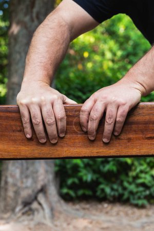Photo for Hands of a middle-aged man on a wooden plank outdoors in natural light. Vertical photography with copy space - Royalty Free Image