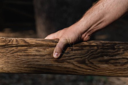 Photo for Hand of a middle-aged man holding a wooden log outdoors with natural light. Horizontal photography - Royalty Free Image