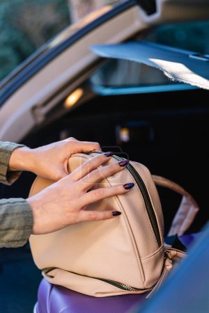 Photo for Young woman loading her luggage in the trunk of the car. Detail of hands. Concept of preparation of the trip - Royalty Free Image