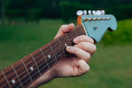 Téléchargez les photos : Gros plan de la main de l'homme jouant de la guitare acoustique. Instrument de musique pour loisirs ou hobby concept de passion - en image libre de droit