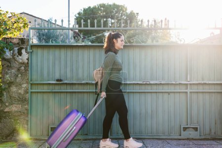 Photo for Casual young woman with suitcase and backpack starting a trip at sunset. Copy space. Travel and vacation concept - Royalty Free Image