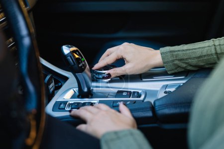 Photo for Close up of female hand operating the on-board computer joystick of her high-end automatic car. Driving concept and vehicle equipment - Royalty Free Image