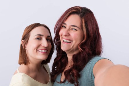 Photo for 2 Young women laughing and looking at camera while taking a selfie. Friendship concept - Royalty Free Image