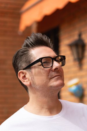 Foto de Retrato al aire libre de un hombre atractivo en sus 50 años con un peluquín y gafas al aire libre en un día soleado. Concepto de madurez y visión - Imagen libre de derechos