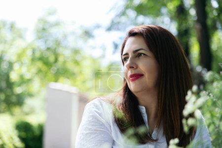 Photo for Portrait of a relaxed and happy 45 year old mature woman looking to the side and enjoying nature on a sunny day. Concept of maturity, happiness and lifestyle - Royalty Free Image