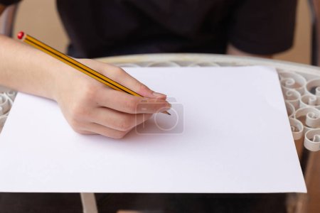 Photo for Hand of a teenage girl with a pencil on a blank sheet in natural light. Concept of creativity, leisure and lifestyle - Royalty Free Image