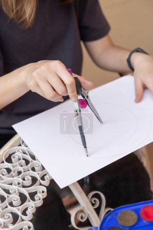 Photo for Teenage girl outdoors making circles on a sheet using a compass. Natural light. Concept of creativity, leisure and lifestyle - Royalty Free Image