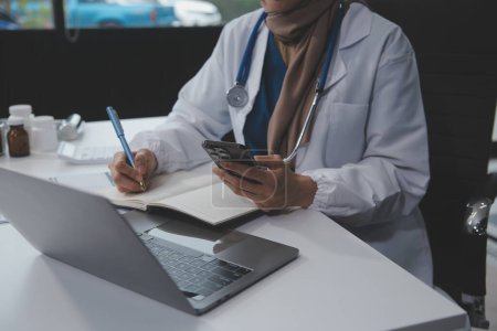 Téléchargez les photos : Médecin femme assise au bureau et rédigeant une ordonnance pour sa patiente - en image libre de droit