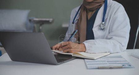 Female doctor sitting at desk and writing a prescription for her patient