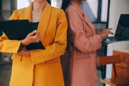 Téléchargez les photos : Asiatique femme d'affaires en costume formel au bureau heureux et joyeux lors de l'utilisation du smartphone et de travail - en image libre de droit