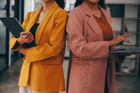 Téléchargez les photos : Asiatique femme d'affaires en costume formel au bureau heureux et joyeux lors de l'utilisation du smartphone et de travail - en image libre de droit