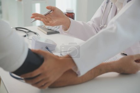 El médico masculino usa un monitor de presión arterial para verificar la presión corporal y el pulso de los pacientes que acuden al hospital para chequeos, tratamiento médico y concepto de atención médica..