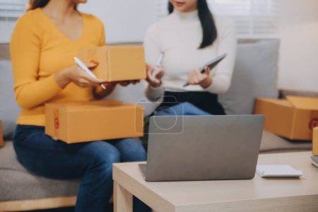 Asian SME business women use laptop computer checking customer order online shipping boxes at home. Starting Small business entrepreneur SME freelance. Online business, Work at home concept.