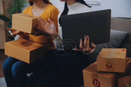 Asian SME business women use laptop computer checking customer order online shipping boxes at home. Starting Small business entrepreneur SME freelance. Online business, Work at home concept.