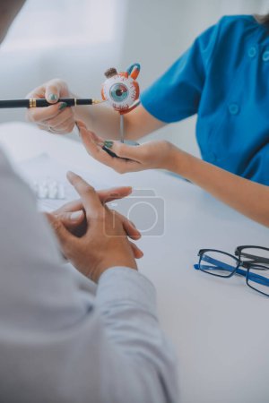 Foto de Primer plano de la doctora asiática hablando con una paciente anciana mostrando el modelo de globo ocular y explicando la enfermedad ocular en el hospital - Imagen libre de derechos