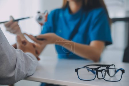 Foto de Primer plano de la doctora asiática hablando con una paciente anciana mostrando el modelo de globo ocular y explicando la enfermedad ocular en el hospital - Imagen libre de derechos