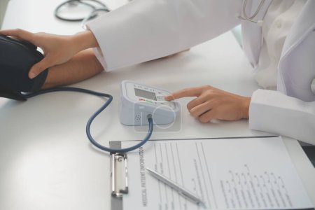 El médico masculino usa un monitor de presión arterial para verificar la presión corporal y el pulso de los pacientes que acuden al hospital para chequeos, tratamiento médico y concepto de atención médica..
