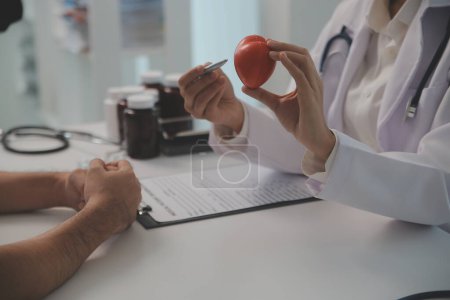 Hands of doctor woman holding red heart, showing symbol of love, human support to patient, promoting medical insurance, early checkup for healthcare, cardiologist help. Close up of object