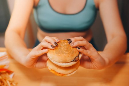 Binge-Eating-Störungskonzept: Frau isst Fast-Food-Burger, gebranntes Huhn, Donuts und Desserts