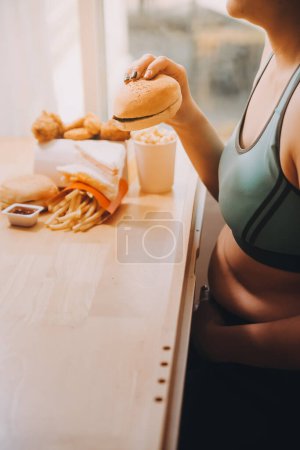 Concepto de trastorno alimenticio excesivo con la mujer comiendo hamburguesa de comida rápida, pollo despedido, rosquillas y postres