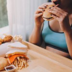 Binge eating disorder concept with woman eating fast food burger, fired chicken , donuts and desserts