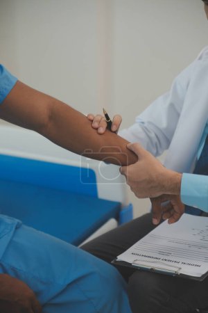 Photo for Close up of doctor sitting on bedside of male patient in hospital - Royalty Free Image
