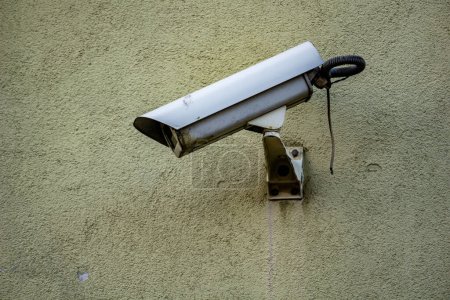Überwachungskamera auf einer grünen Mauer montiert, die das Sicherheitskonzept der staatlichen Überwachung überwacht