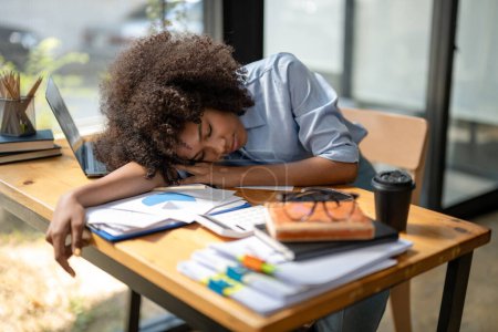 Photo for Black woman taking a nap at the table,  tired from work. - Royalty Free Image