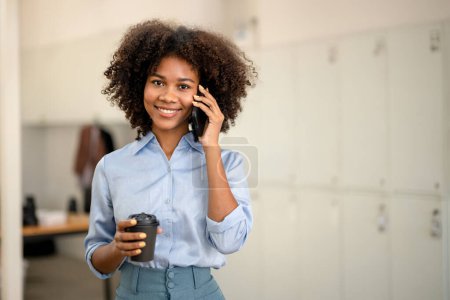 Foto de Mujer de negocios sosteniendo una taza de café y disfrutando de una llamada telefónica, sonrisa y mirando al fotógrafo - Imagen libre de derechos