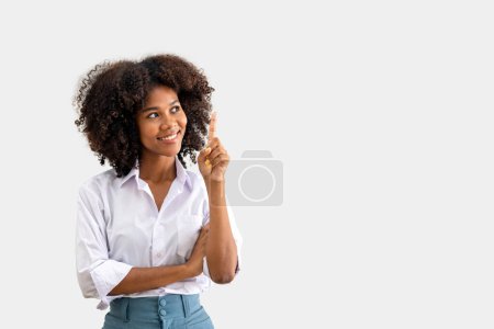 Foto de Mujer negra señalando con el dedo hacia arriba en el copyspace aislado sobre fondo blanco. idea de pensamiento empresarial. moviendo un dedo en señal de lo mejor - Imagen libre de derechos