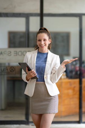Foto de Mujer de negocios inteligente de pie sosteniendo tableta digital en la oficina. - Imagen libre de derechos