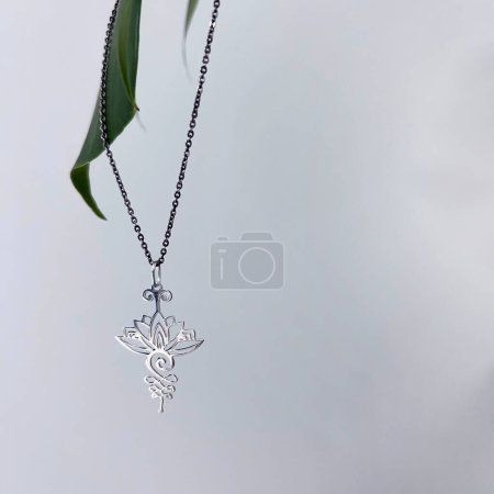 Silver lotus pendant on natural white background with green leaf
