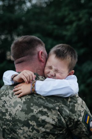 Un petit garçon dit au revoir à un soldat les yeux fermés. Le fils embrasse le père du soldat ukrainien. Le défenseur ukrainien a dit au revoir à sa famille. Guerre en Ukraine.