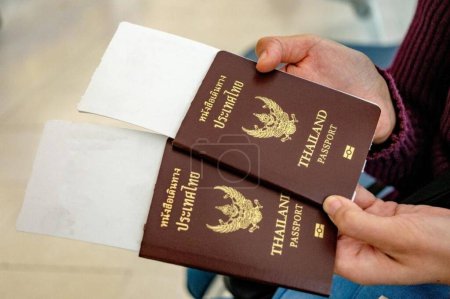 Téléchargez les photos : Deux passeports thaïlandais en mains avec cartes d'embarquement - en image libre de droit