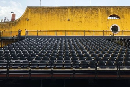 Téléchargez les photos : Rangées de sièges vides dans un stade de football avec mur jaune. - en image libre de droit