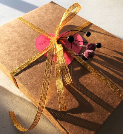 Foto de Caja de regalo con corazón rojo y cinta dorada sobre fondo blanco. - Imagen libre de derechos