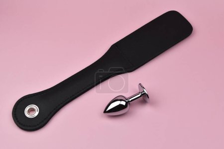 Photo for Anal sex concept, anal plug and spanking device on a pink background, slave spank paddle, accessories for adult sexual games, sex toys for BDSM, adult whip - Royalty Free Image