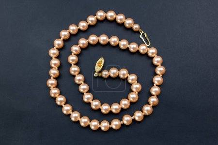 Pearl necklace on a black background. Top view. Flat lay.
