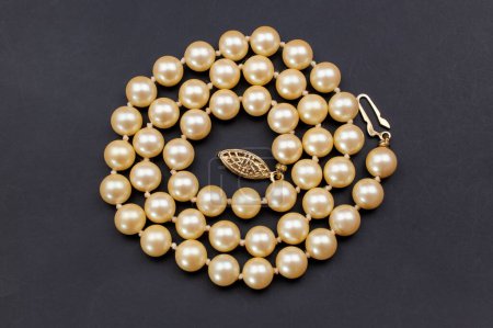 Pearl necklace isolated on black background. Top view, flat lay.